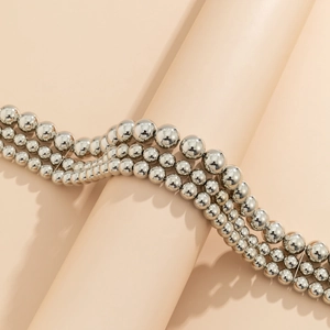 Detailed view of layered silver beaded necklaces featuring a high-polish metallic finish