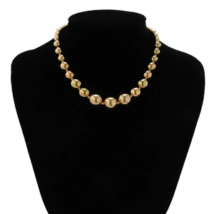 Macro detail of high-polish gold layered beaded choker necklace on a black jewelry stand