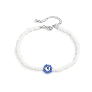 Detalle del collar de cuentas blancas con flor azul y amuleto de la letra R grabada