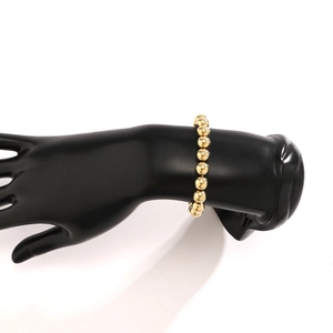 Detailed view of polished gold bead bracelet with high-gloss finish on a black hand model