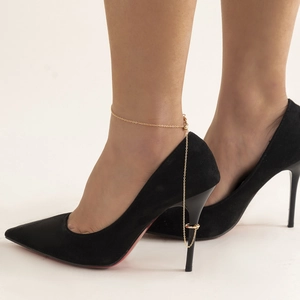 Detail of adjustable gold bead chain anklet connected to a high heel ring decoration