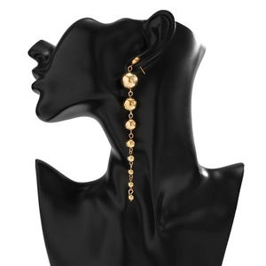 Detail of long gold tiered ball drop earrings hanging on a black model stand