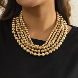 Close-up of multilayered gold beaded punk necklaces on a model wearing a black shirt
