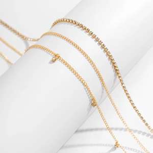 Détail d'une chaîne de corps dorée multicouche avec maillons cristal et pendentif rond