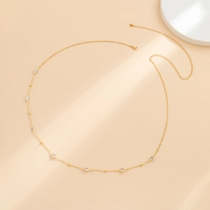 Detail of a thin gold waist chain with clear crystals and adjustable lobster clasp