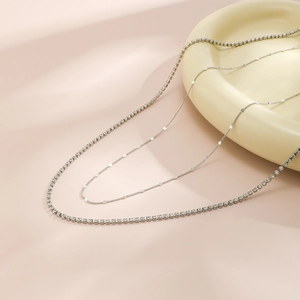 Close-up of double layer silver chain set with minimalist discs and sparkling tennis chain