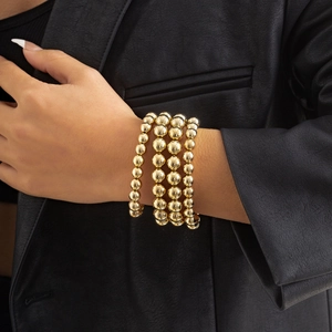 Close-up of layered gold beaded bracelet with high-polish finish on model wrist