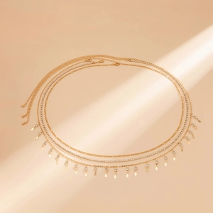 Détail d'une chaîne de taille dorée à trois couches avec strass et pendentifs gouttes