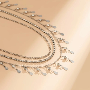 Détail d'un collier multicouche argenté avec des strass et des pendentifs goutte d'eau