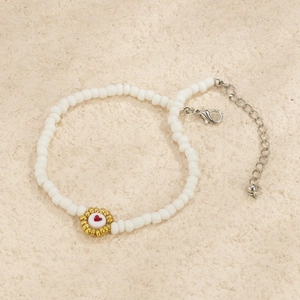 Vista macro detallada de pulsera de cuentas blancas con dije de corazón dorado y cierre