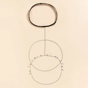 Detail of star and moon charms with colorful beads on a layered silver thigh chain