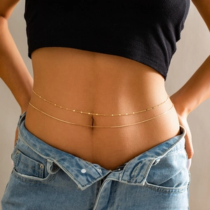 Detail of a double-layered gold waist chain with delicate disc charms on a model