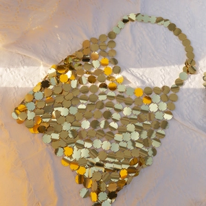 Macro shot of shimmering gold sequin discs and metallic chain links of the disco body bag