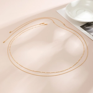 Detail of double-layered gold chain body jewelry with small metal discs and snake chain