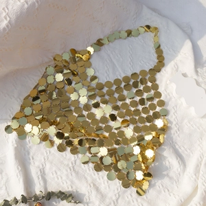 Close-up of gold metal sequins and hollow chain links on a tassel halter top