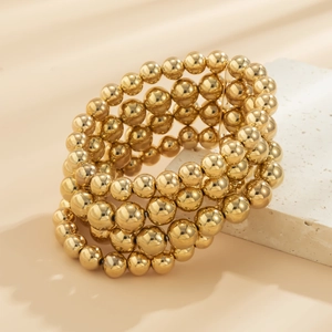 Detail shot of five-piece gold beaded bracelets set on elegant stone background