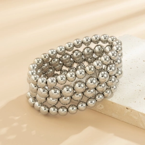 Close-up of a four-layer silver beaded punk bracelet displayed on a natural stone base