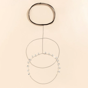 Detail of silver thigh chain with elastic band and heart charms on beige background