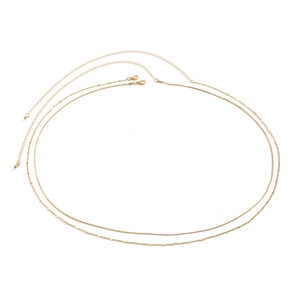 Detail of golden double-layer body chain featuring sleek snake chain and round disc charms