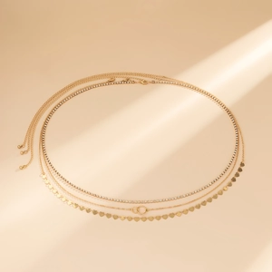 Détail de la chaîne de taille multicouche dorée avec strass et breloques en cœur