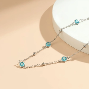 Detail of silver body chain featuring light blue crystal beads and metallic round accents