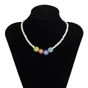 Detalle del collar de cuentas blancas con colgantes de flores coloridas y letras LOVE