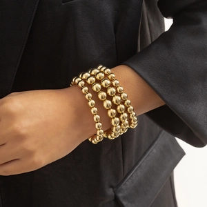 Layered gold beaded bracelet stack with four strands featuring a polished metallic finish