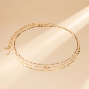 Détail de chaînes de taille dorées à plusieurs niveaux avec strass et pendentifs