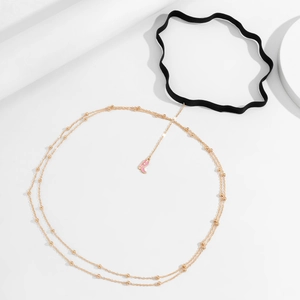 Detail of pink western boot pendant on gold layered thigh chain with black elastic band