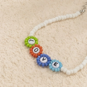 Detalle de cuentas de flores de colores con letras LOVE en un collar de cuentas blancas