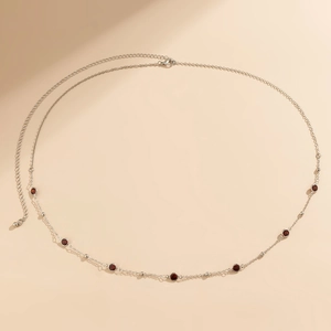 Detail of silver body chain featuring red crystal beads and adjustable extender