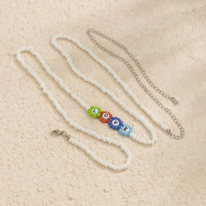Detalle del collar de perlas blancas con cuentas de letras LOVE florales de colores