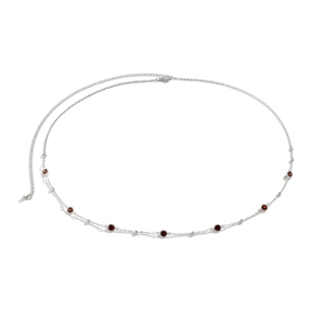 Macro detail of silver body chain featuring deep red gemstones and adjustable lobster clasp