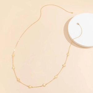 Detail showing gold hip-hop chain with starburst pendants on a minimal beige background