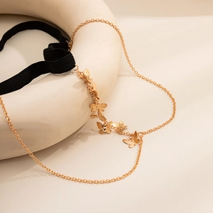 Detail of gold butterfly thigh chain with layered charms and black elastic band