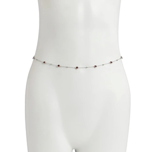 Close-up of slender silver body chain featuring round red crystal accents on a waist