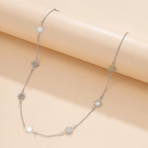 Macro detail of silver sunburst star charms on a chunky layered hip-hop metal chain