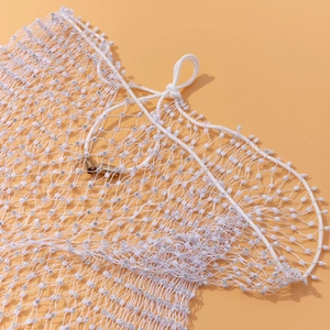 Détail du haut en résille blanche avec strass scintillants et perles sur fond pêche