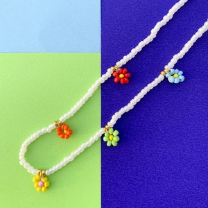Dettaglio della collana di perline fatta a mano con margherite colorate e bianche