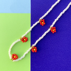 Dettaglio della collana fatta a mano con perline bianche e piccoli fiori margherita