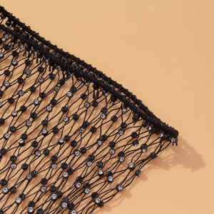 Détail du tissu en maille noire avec strass brillants et perles noires décoratives