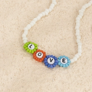 Primer plano de cuentas de flores de colores con LOVE en un collar de perlas