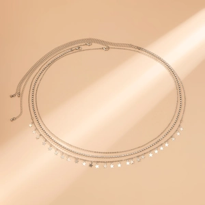 Détail d'une chaîne de corps argentée multicouche avec breloques étoiles et strass brillants