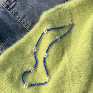 Dettaglio della collana a margherite con perline blu e chiusura a moschettone argento
