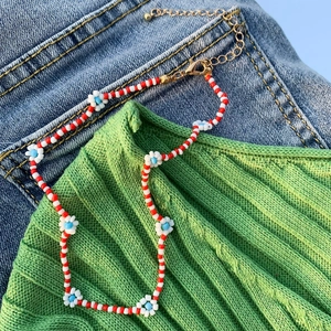 Dettaglio della collana bohémien a margherita con perle rosse e bianche e chiusura a moschettone