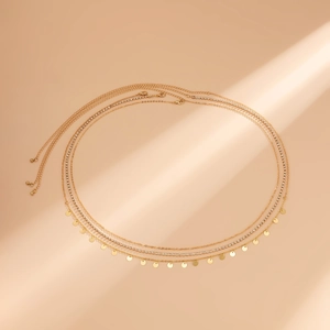 Détail d'une chaîne de corps dorée multicouche avec des paillettes et des strass brillants