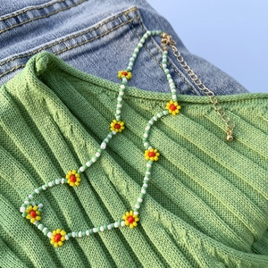 Dettaglio della collana fatta a mano con margherite, perline verdi e chiusura dorata