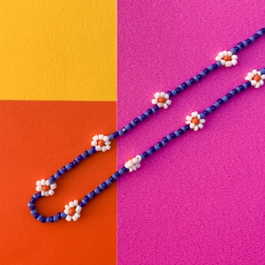 Dettaglio della collana fatta a mano con perline a margherita su sfondo vivace