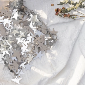 Close-up of silver mirror star body chain with fringe details on white textured fabric