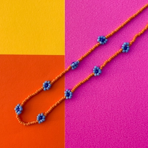 Dettaglio della collana di perline arancioni con accenti di margherite blu in stile Y2K
